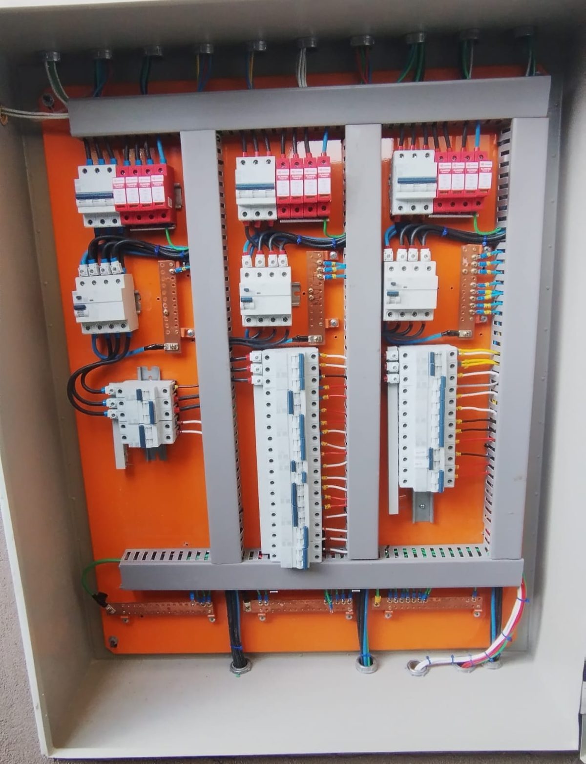Quadro de distribuição com três colunas de circuitos, disjuntores em trilho DIN, canaletas e condutores separados por fase